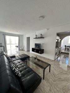 a living room with a black leather couch and a table at Vivienda en Arrecife de 4 habitaciones in Arrecife