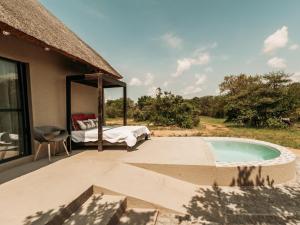 フッドスプルイトにあるMaroelani Lodge- Greater Kruger Private Reserveのベッドルーム1室、パティオ(ベッド1台、スイミングプール付)が備わります。