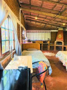 Habitación con 2 camas, mesa y ventanas. en Cabaña Kinti Yuraq en Kinti Wasi, en Cajamarca