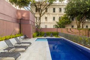 a swimming pool with lounge chairs and a building at Club Haas Higienópolis in São Paulo