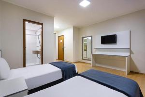 サンパウロにあるカリヨン プラザ ホテルのベッド2台とテレビが備わるホテルルームです。