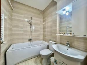 a bathroom with a tub and a toilet and a sink at Catalina Summerland Apartaments Mamaia Nord in Mamaia
