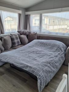 a bedroom with a bed and a couch with windows at Alberta holiday park in Whitstable