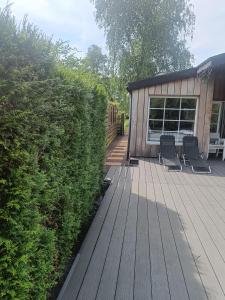 two chairs on a wooden deck next to a building at Time 2 Relax chalet aan het water in Geel
