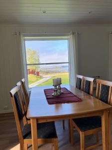 stół jadalny z krzesłami i duże okno w obiekcie Feriehus og naust i idylliske omstendigheter w mieście Tjørvåg