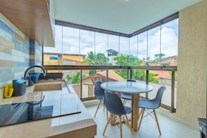 a kitchen with a table and chairs and a large window at Tangaroa Flats em Porto de Galinhas por Carpediem in Porto De Galinhas