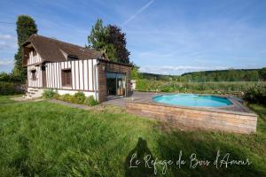 une maison avec une piscine dans une cour dans l'établissement Le Refuge du Bois d'Amour, à Arnières-sur-Iton