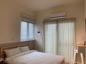 a bedroom with a bed and a window with a air conditioner at Fish Tears B&B in Magong