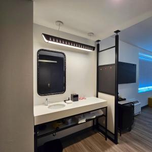 uma casa de banho com um lavatório e uma televisão na parede em Aloft McAllen em McAllen