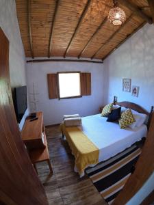 een slaapkamer met een bed, een bureau en een televisie bij Chalés Vila Carrancas - Unidade Centro in Carrancas