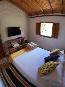 um quarto com uma cama grande e uma televisão em Chalés Vila Carrancas - Unidade Centro em Carrancas