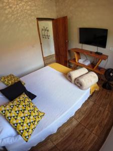 a bedroom with a bed with two pillows and a television at Chalés Vila Carrancas - Unidade Centro in Carrancas