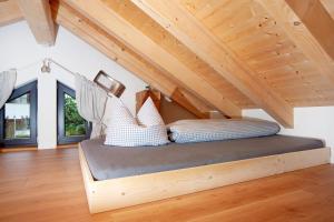 a bed in a room with a wooden ceiling at Schorenmoos Lodge in Dietmannsried