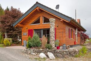a log cabin with a stone wall at Schorenmoos Lodge in Dietmannsried