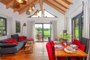 a living room with a table and red chairs at Schorenmoos Lodge in Dietmannsried