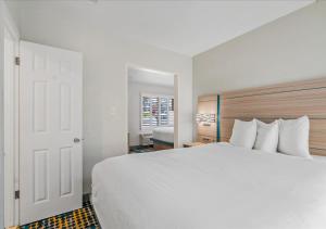 - une chambre avec un grand lit blanc et une fenêtre dans l'établissement Pacific Shores Inn - Morro Bay, à Morro Bay