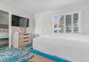 a white bedroom with a large bed and a flat screen tv at Pacific Shores Inn - Morro Bay in Morro Bay