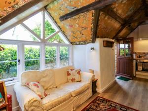 a living room with a couch and some windows at Toad Hall Cottage in Totnes