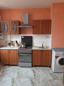 eine Küche mit Holzschränken, einem Herd und einer Spüle in der Unterkunft Buxara apartment 