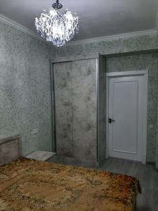 ein leeres Zimmer mit einer Tür und einem Kronleuchter in der Unterkunft Buxara apartment 