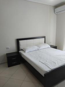 1 cama con marco negro y sábanas y almohadas blancas en Lukova Center Apartments, en Lukovë