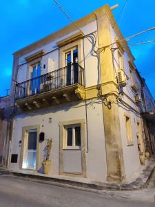 a yellow and white building with a balcony at Kalsa’s House Noto in Noto