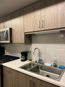 a kitchen with a stainless steel sink and wooden cabinets at 1 Bdr Apt in Irvine - Near John Wayne in Irvine