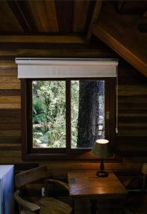 ein Fenster in einer Hütte mit einem Tisch und einer Lampe in der Unterkunft Parador Hampel in São Francisco de Paula
