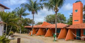 een oranje gebouw met palmbomen ervoor bij Pousada Tupi Imbassai in Imbassai