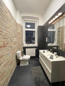 ein Badezimmer mit einem Waschbecken, einem WC und einer Ziegelwand in der Unterkunft Alice Apartment in Budapest