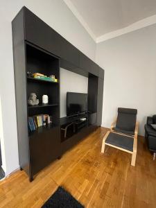 ein Wohnzimmer mit einem schwarzen Bücherregal und einem Stuhl in der Unterkunft Alice Apartment in Budapest