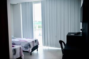 hotel quatro coracoes في أرابيراكا: غرفة نوم بسرير ونافذة كبيرة