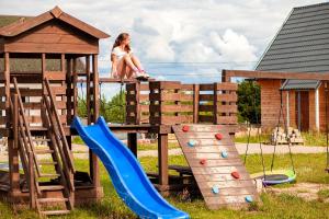 a woman sitting on top of a wooden playground at Stilo Country Dargobądz in Wolin