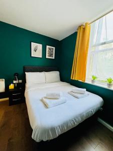 a bedroom with a white bed with a green wall at Private Studio Flat in City 1190 in London