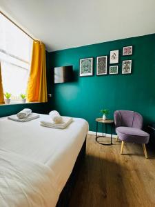 a bedroom with a large bed and a purple chair at Private Studio Flat in City 1190 in London