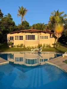 a house with a swimming pool in front of it at Pousada Cantoria in Cumuruxatiba