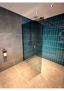 a bathroom with a shower with a blue tiled wall at Hotel Brasserie Smits in Wemeldinge
