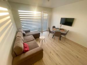 uma sala de estar com um sofá e uma mesa em Duneville Apartments Mano Jūra 2 em Palanga