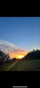 einen Sonnenuntergang auf einem Feld mit der Sonne am Himmel in der Unterkunft Noclegi w Dolinie Wilkowskiej in Wilków