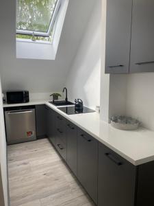 cocina con encimeras blancas, fregadero y ventana en Noclegi w Dolinie Wilkowskiej en Wilków