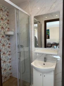 een witte badkamer met een wastafel en een douche bij Pokoje Gościnne - Apartamenty MATI in Kopalino