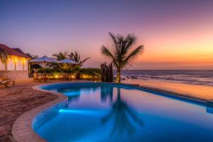a swimming pool next to the beach at sunset at Yemaya Boutique Hotel en Canoas in Canoas de Punta Sal