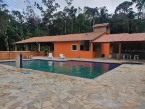 a swimming pool in front of a house at Chácara Rosa Maria in São Paulo
