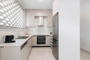 a kitchen with white cabinets and a stainless steel refrigerator at Zante Melina's Apartment in Argassi +11 photos