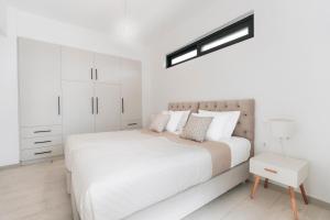 a white bedroom with a bed and a white cabinet at Zante Melina's Apartment in Argassi