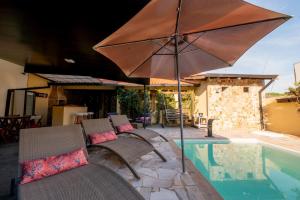 a patio with chairs and an umbrella next to a pool at Pousada no coração de Londrina in Londrina