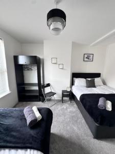 a bedroom with two beds and a chair at Gillingham 4 bed Guest House in Gillingham
