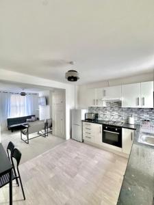 a kitchen with white cabinets and a living room at Gillingham 4 bed Guest House in Gillingham