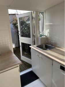 uma cozinha branca com um lavatório e uma janela em Luna em Marstal