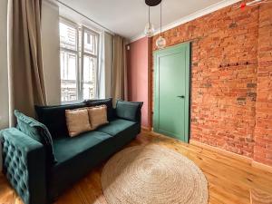 a living room with a green couch and a brick wall at Central Old Town Apartment in Gdańsk